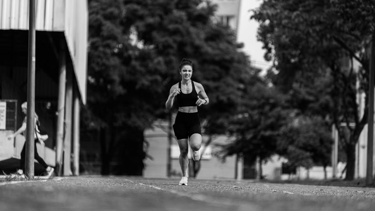 A young woman runs energetically outdoors, captured in a dynamic black and white photo.